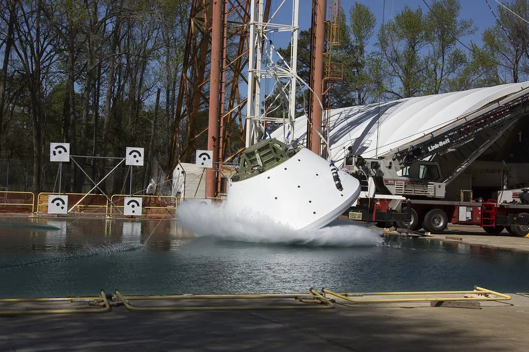 An Orion crew capsule test article dropping into a large water basin at NASA Langley Research Center